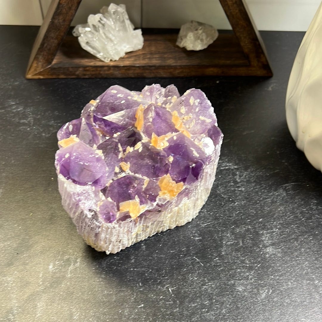 Amethyst cluster with orange calcite speckled throughout on a black background.