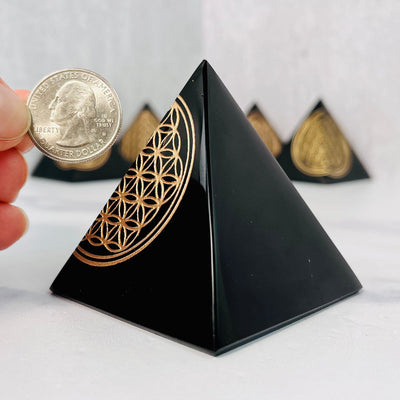 Side view of Black Obsidian Flower of Life Mini Pyramid, pictured next to a quarter for size reference.