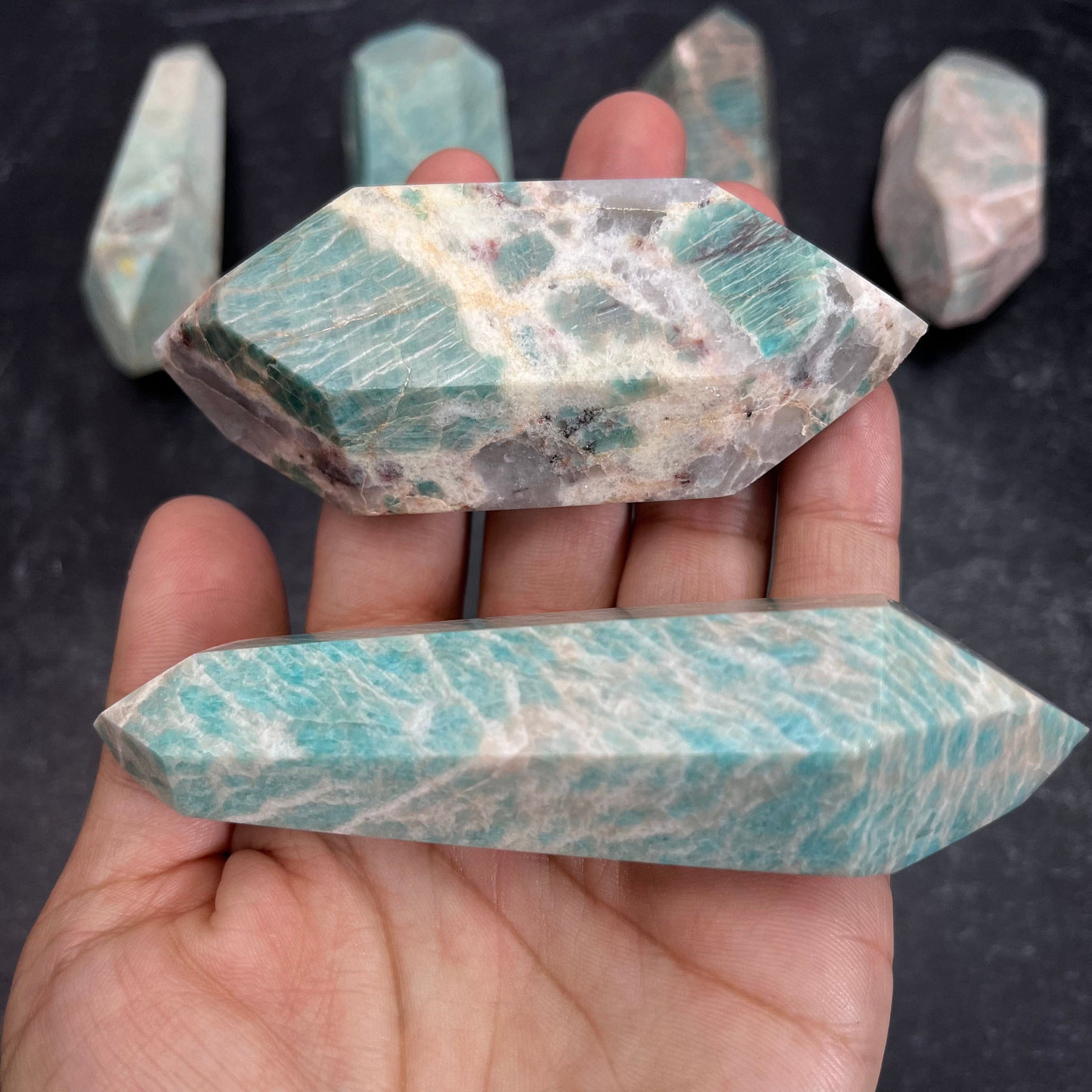 Two Amazonite Polished Double Terminated Points, in the weight range of 100g-150g, laying in palm of woman's hand.