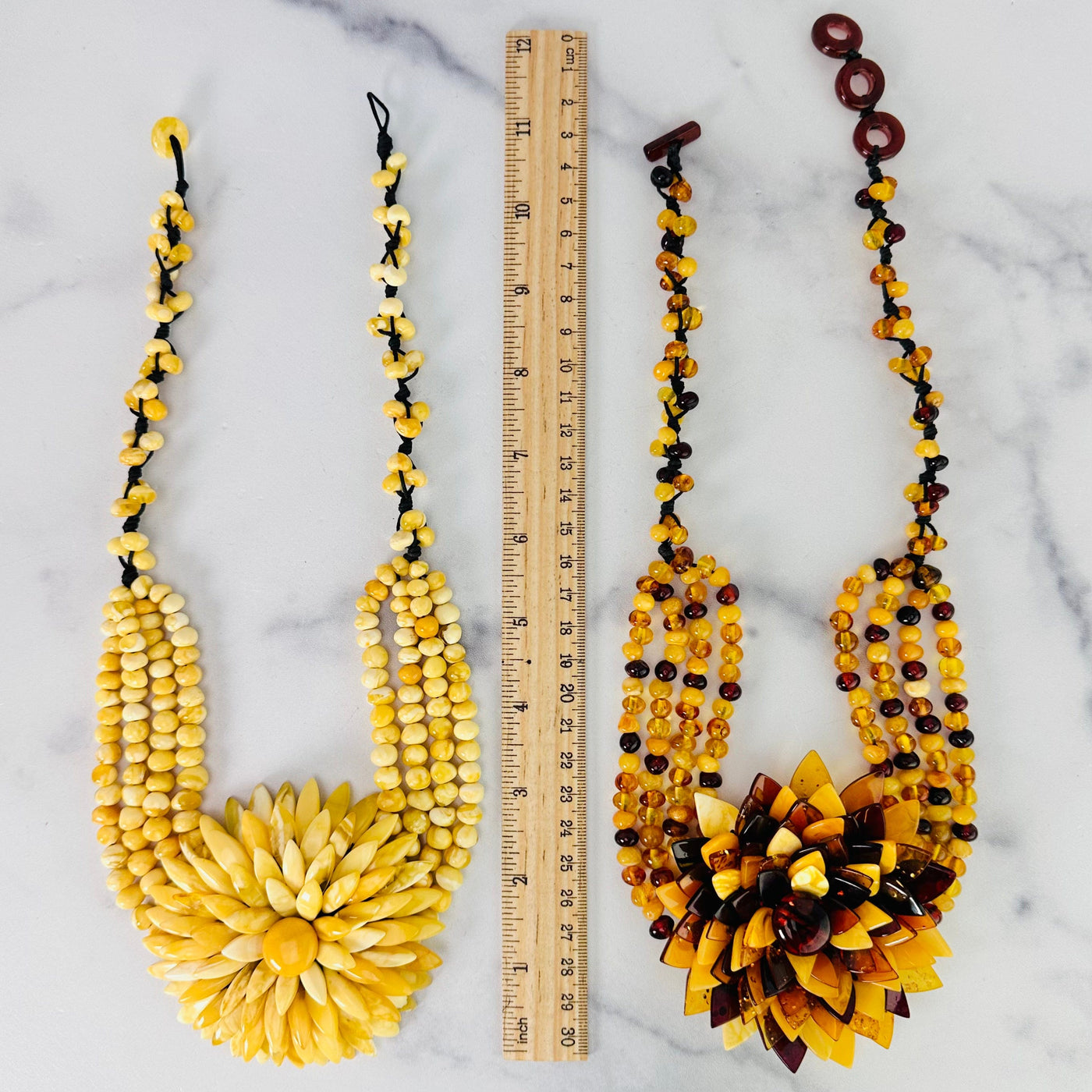 Two Baltic Amber Beaded Flower Necklaces shown on a marble surface with a ruler in between for size reference.