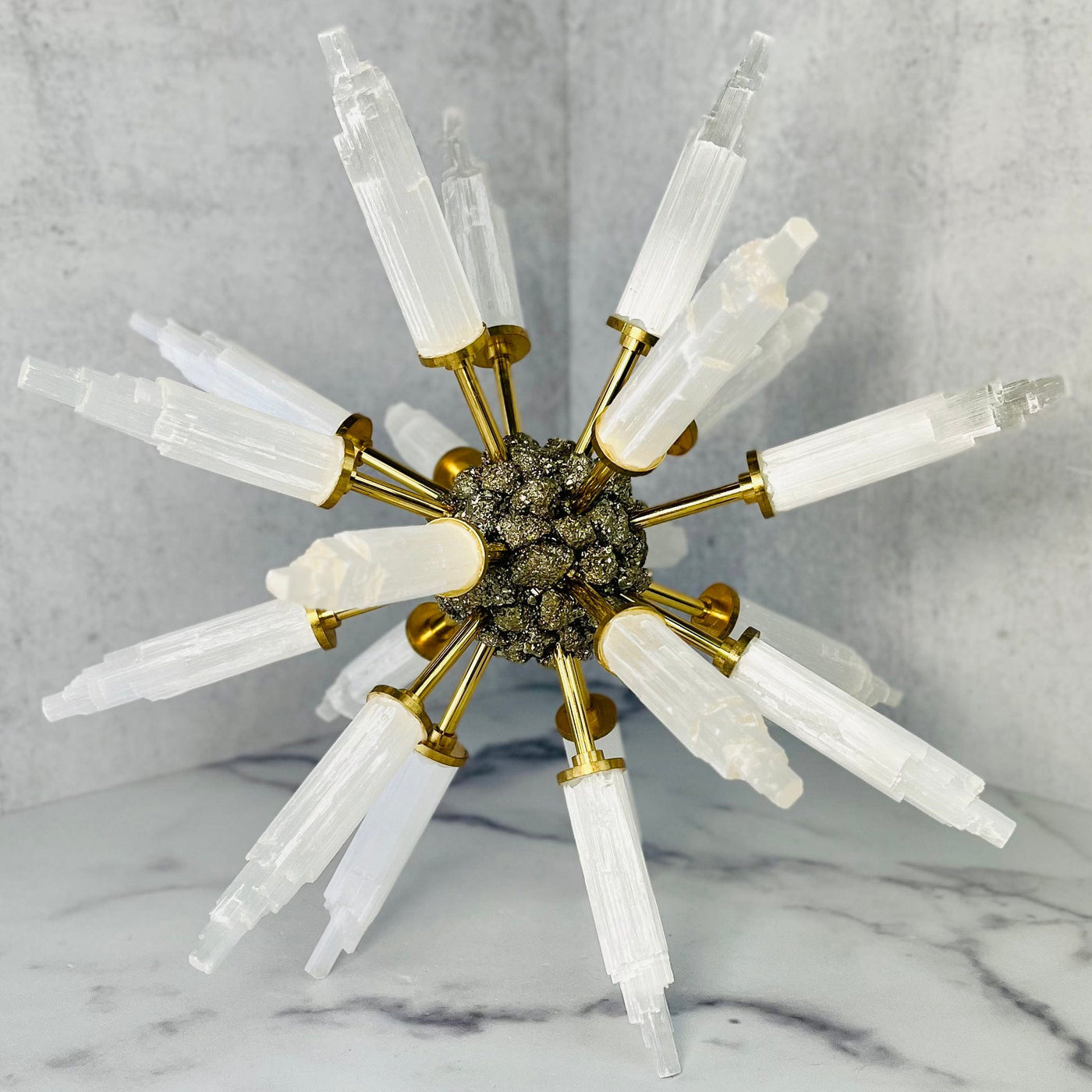 Selenite Point Spike Globe with Pyrite Cluster Center standing on a marble surface.
