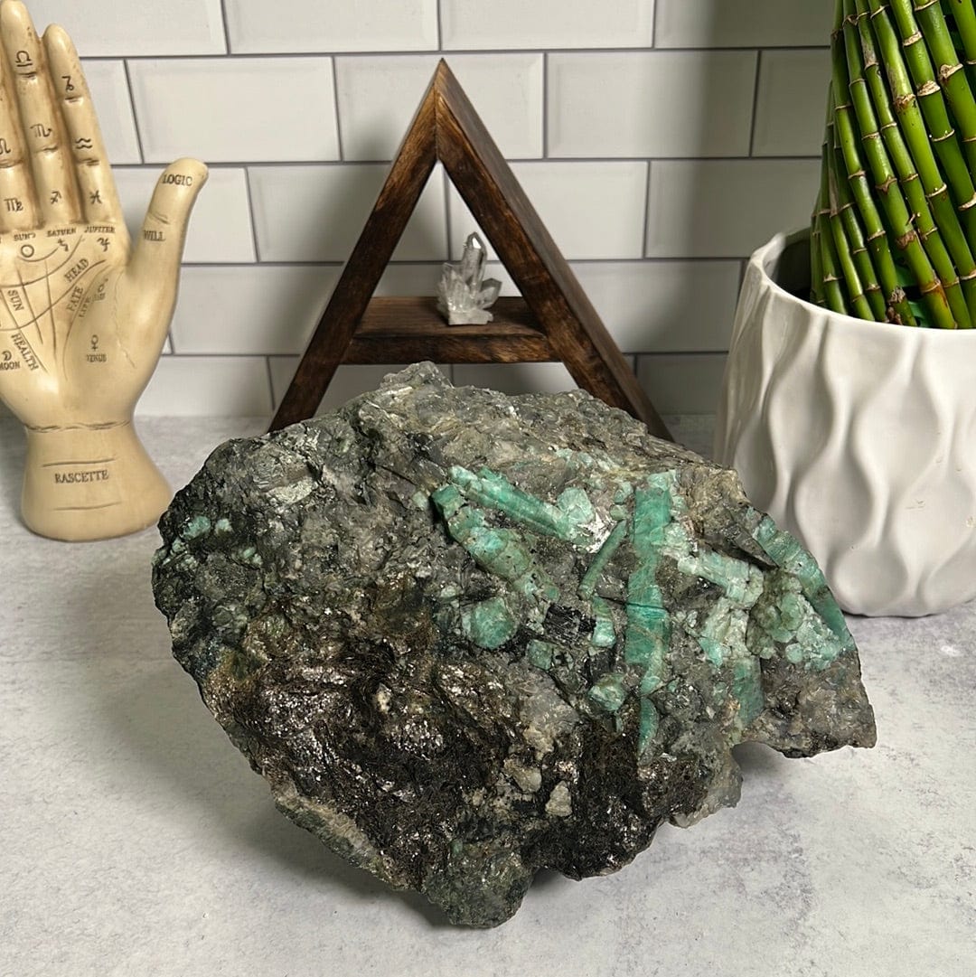 Large emerald rough stone.  It has emerald green rods on a green and black rock matrix.
