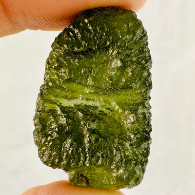 9.2 gram (option N) Moldavite piece held up between woman's fingers.
