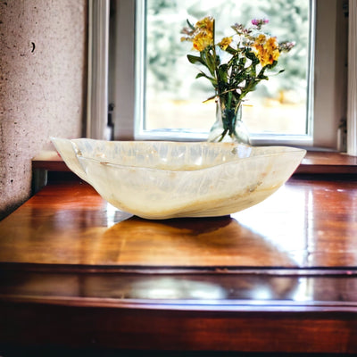 Large mexican onyx bowl displayed on a counter top.  It is shades of cream, tan, and brown.