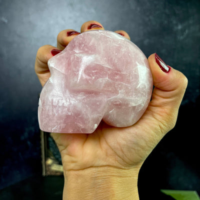 Up close side view of Rose Quartz Polished Skull number 2, held in hand.