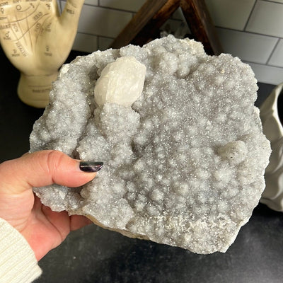 Large gray amethyst druzy cluster with one calcite formation on the top left.