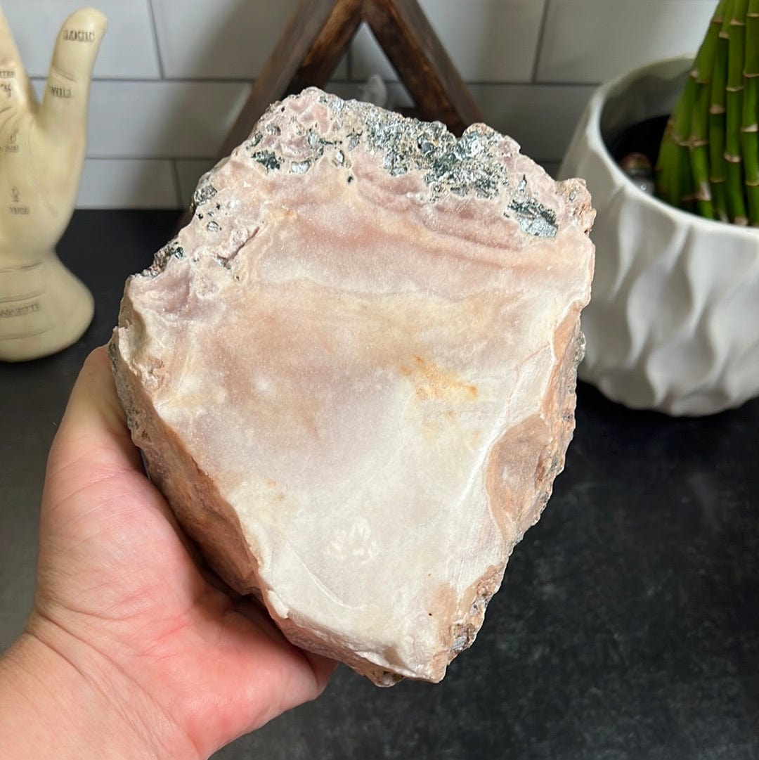 pink amethyst slab removed from the stand and held in a woman's hand.