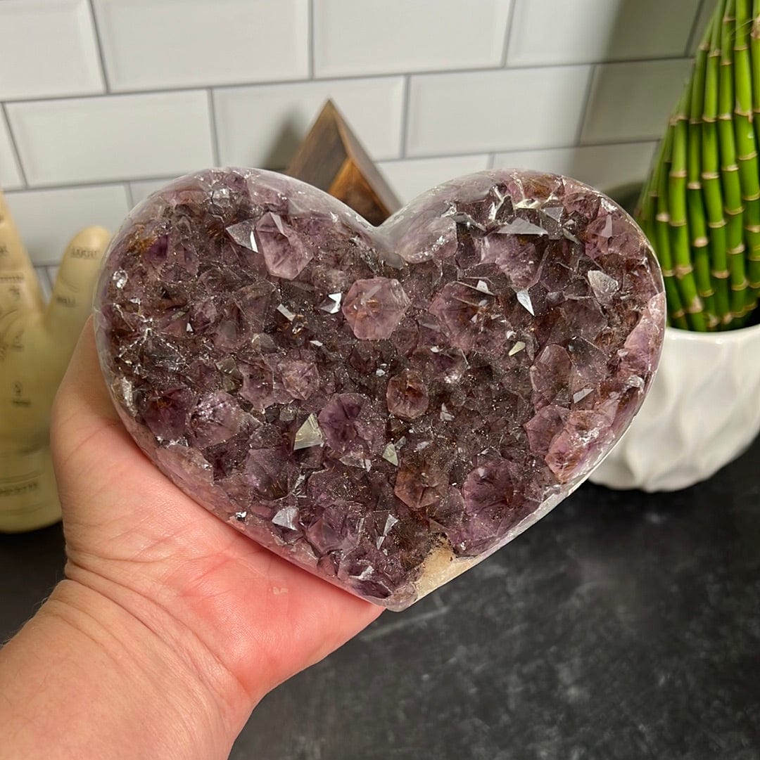 Amethyst cluster heart held in a woman's hand.