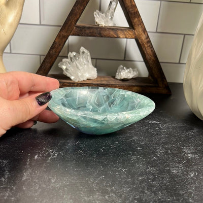 Small green fluorite bowl with a woman's hand next to it.