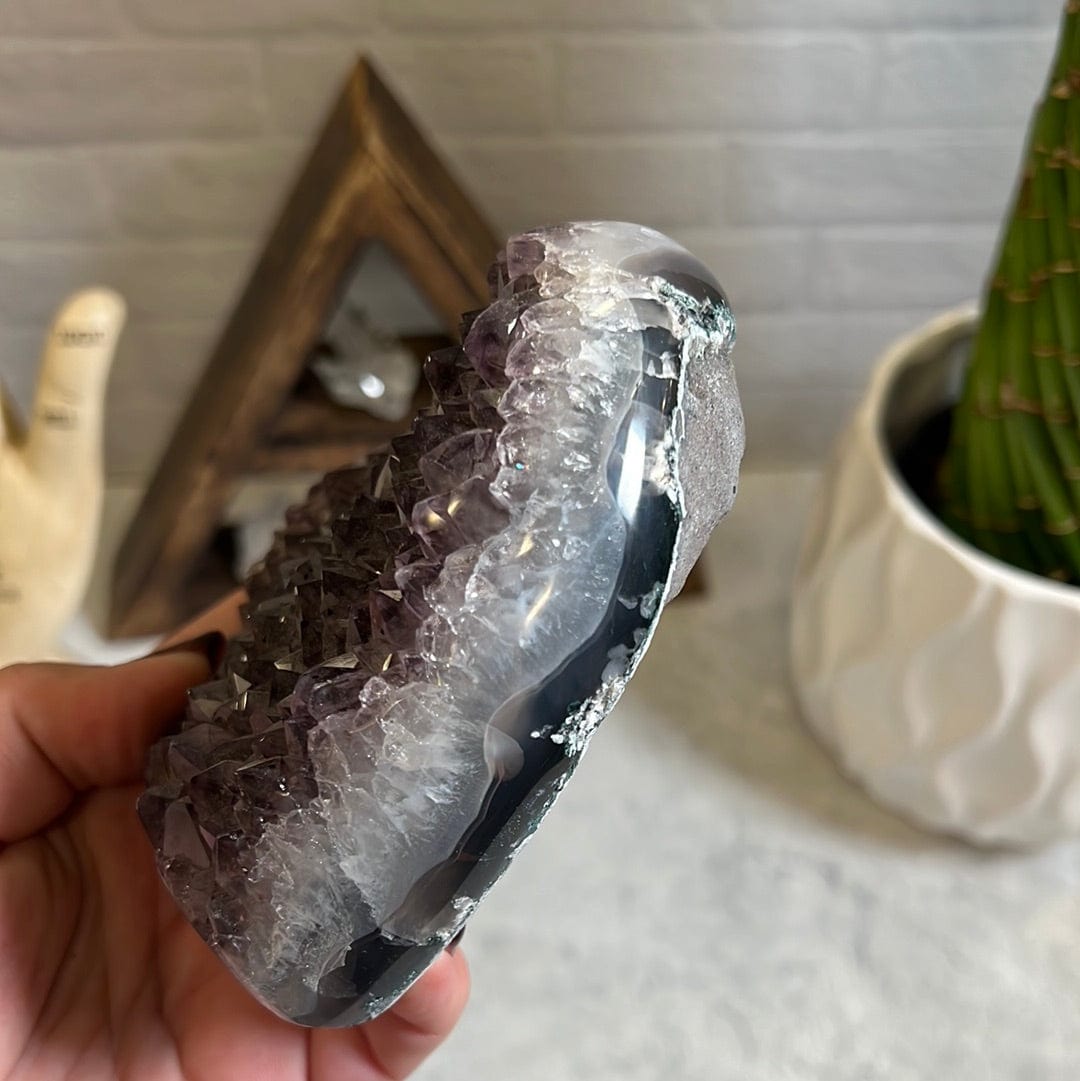 Side view of the amethyst heart showing it is crystal with gray agate banding on the side.