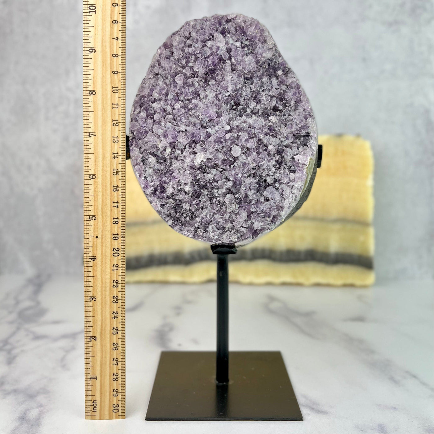 Frontal view of Oval Amethyst Crystal Cluster on Metal Stand next to ruler for size reference