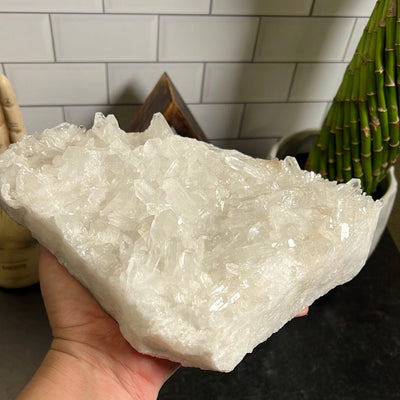 Large triangular shaped crystal cluster held in a woman's hand.