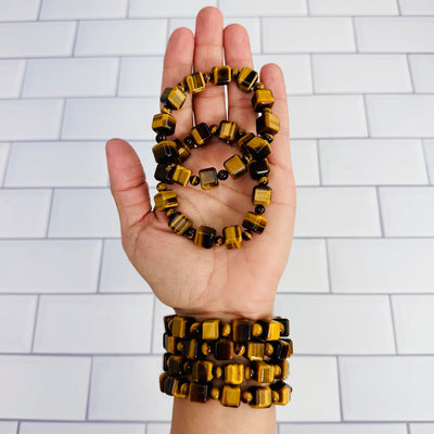6 Tigers Eye cubed bead bracelets displayed, 4 on woman's wrist and 2 in palm of hand.