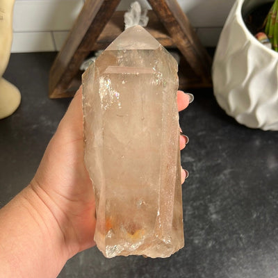 Large smokey quartz point in a woman's hand.