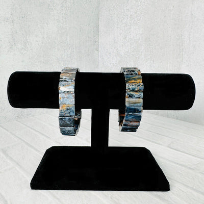 2 Blue Pietersite Rectangle Bead Bracelets on a black bracelet display.