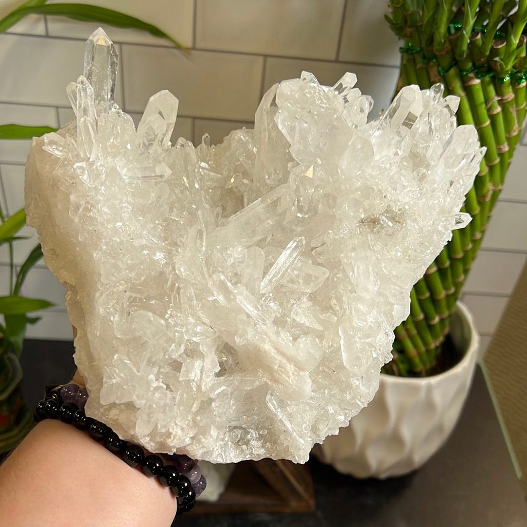 Large crystal quartz cluster held up in a woman's hand.