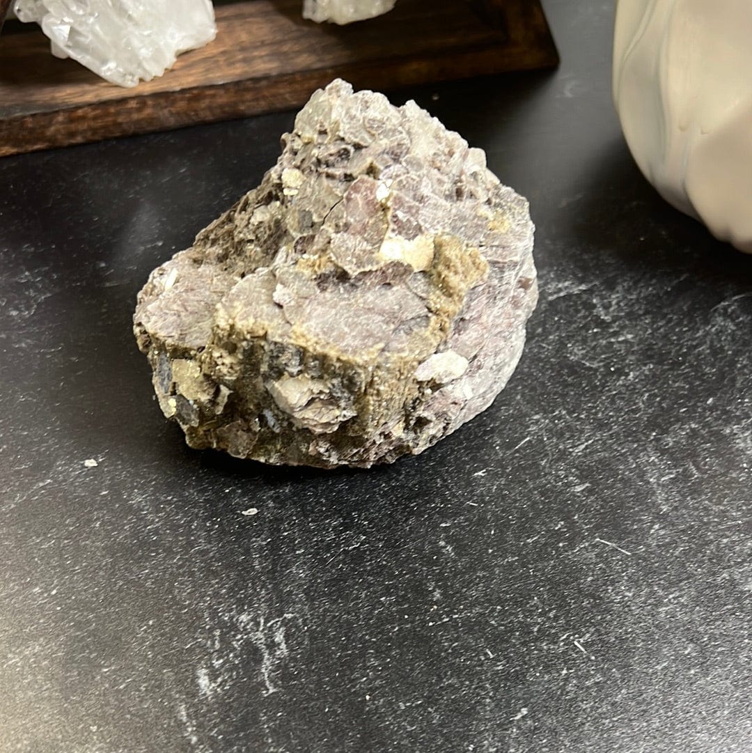 Lepidolite rough stone with golden mica scattered on it.
