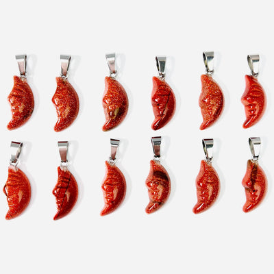 Twelve Goldstone Crescent Moon Gemstones Pendants lined up in two rows on a white surface.