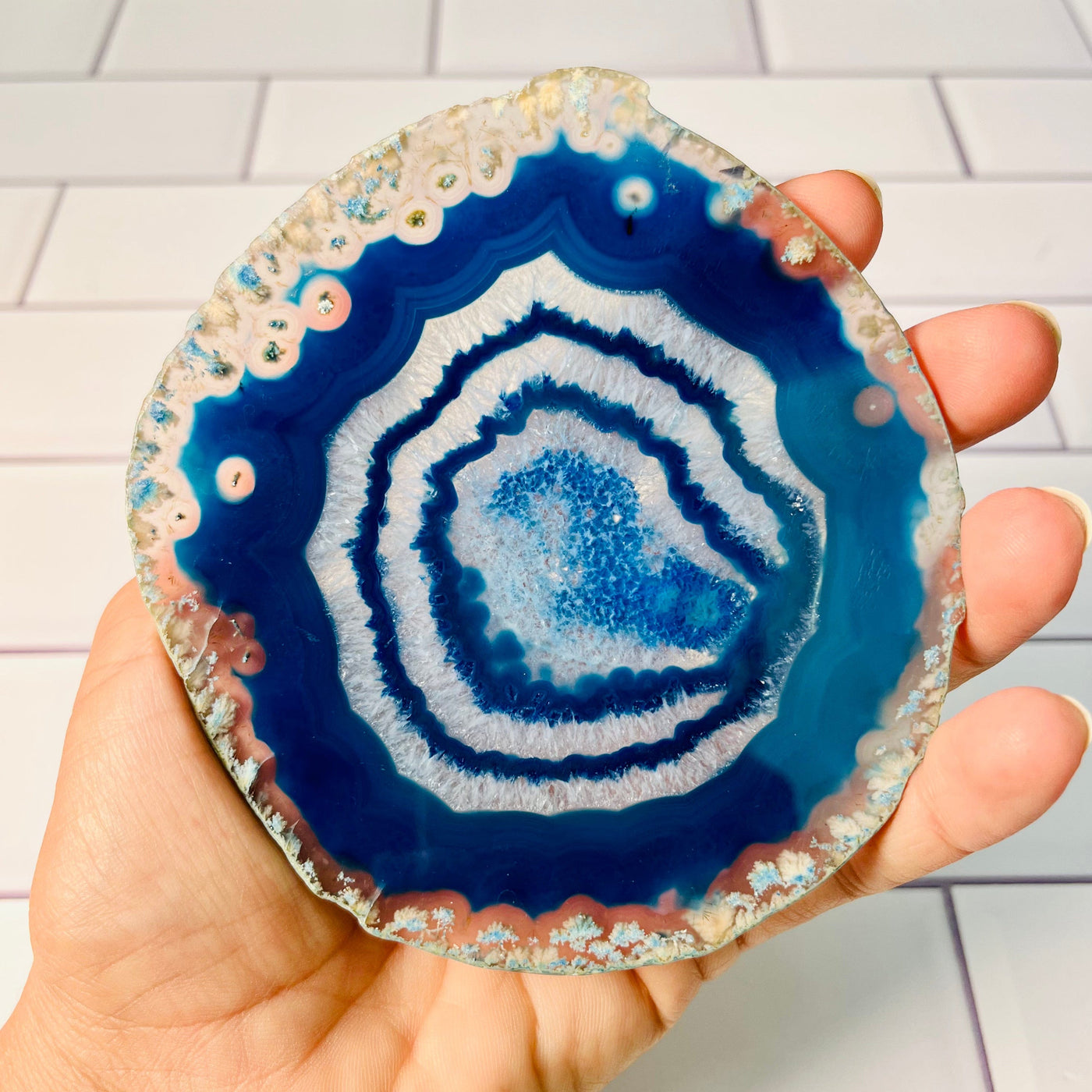 Back view of the mid sized Agate slice, blue white and clear in color, held in woman's hand.