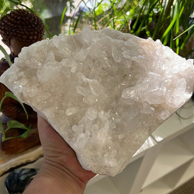 Large triangular shaped crystal cluster held in a woman's hand.