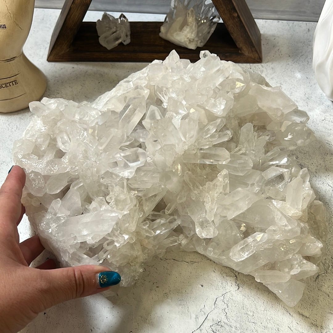 Large crystal cluster with points all over it on a cement background.