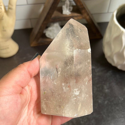 Polished crystal quartz point held in a woman's hand.