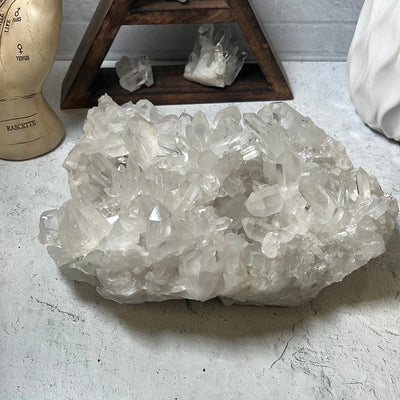 Large crystal cluster with points all over it on a cement background.