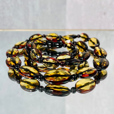 Up close view of Baltic Amber Beaded Necklace, twirled up in layers on a mirrored surface.