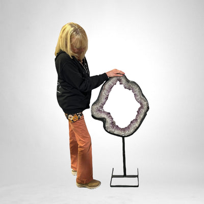 woman standing next to a Large Amethyst Portal on Metal Stand on white background