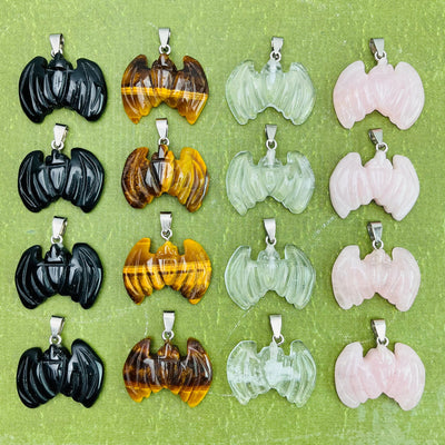 Bat Gemstone Pendants lined up on a green surface, four of each stone.