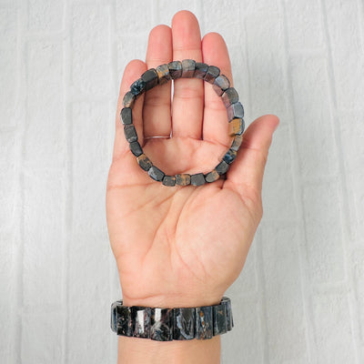 Blue Pietersite bracelets displayed, 1 in palm of hand and 1 around wrist.