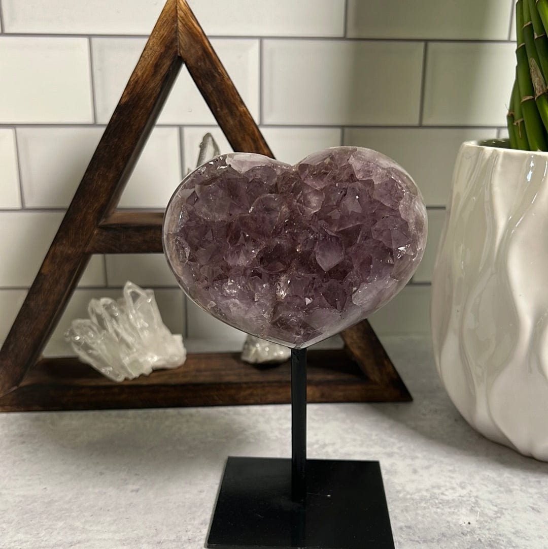 Amethyst cluster heart on a black metal stand.