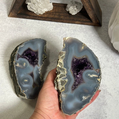An agate geode cut into two halves.  It is gray with a purple amethyst center.