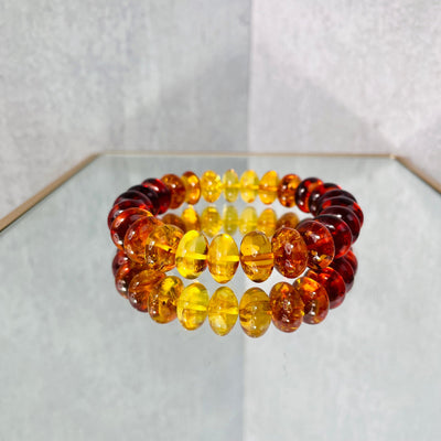 Up close view of Baltic Amber Bracelet on a mirrored surface.