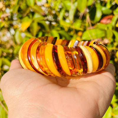 Back view of Baltic Amber Bracelet, held up in palm of woman's hand.