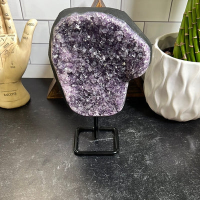 Dark purple amethyst cluster on a black metal stand.