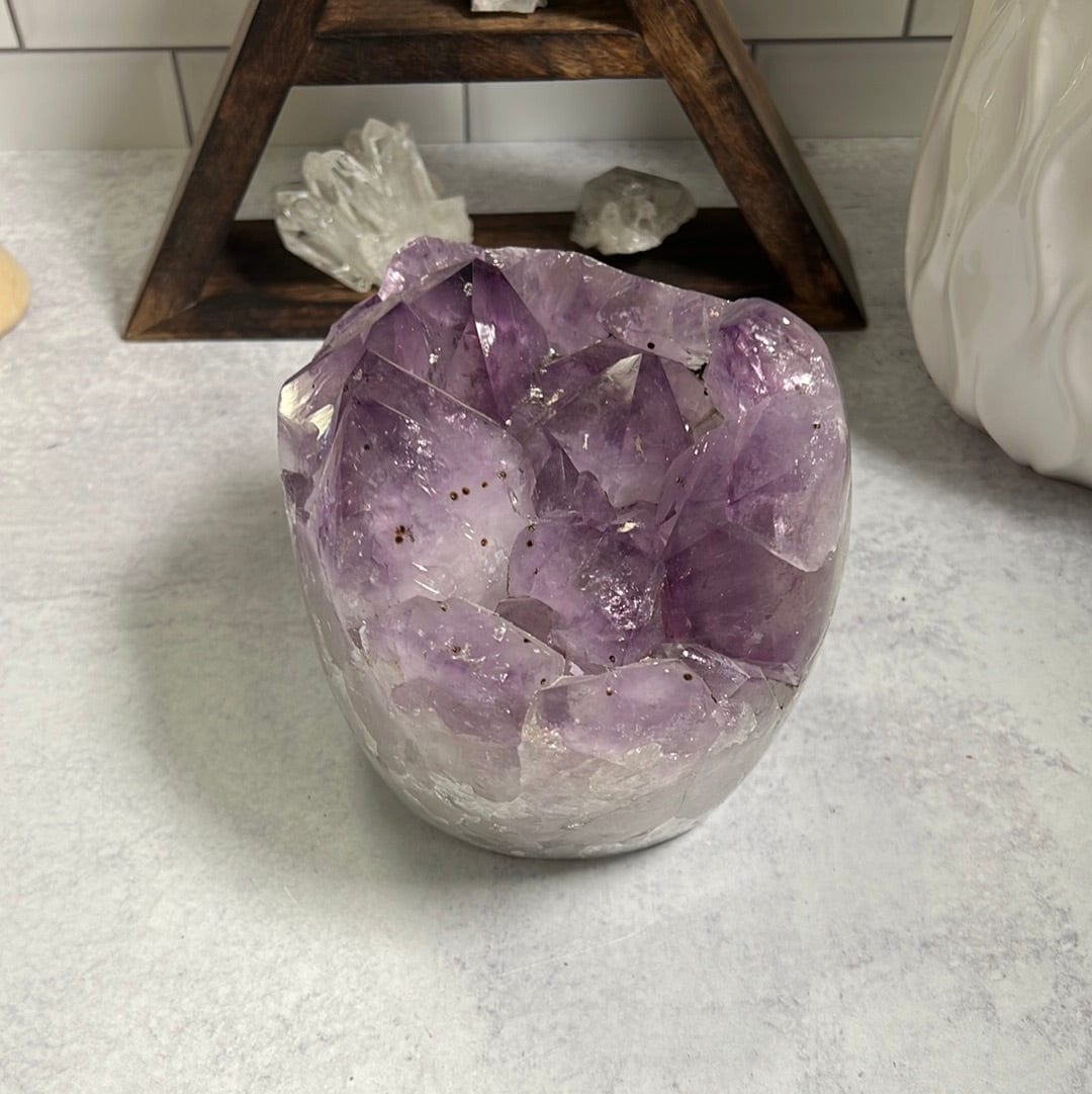Amethyst cluster with polished sides.  The sides are more white and the top clusters are purple with some black speckles.