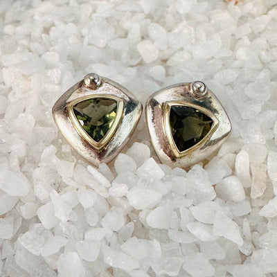 Up close view of Moldavite earrings on top of crystal quartz chips.