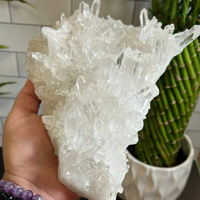 Large crystal cluster held up in a woman's hand.