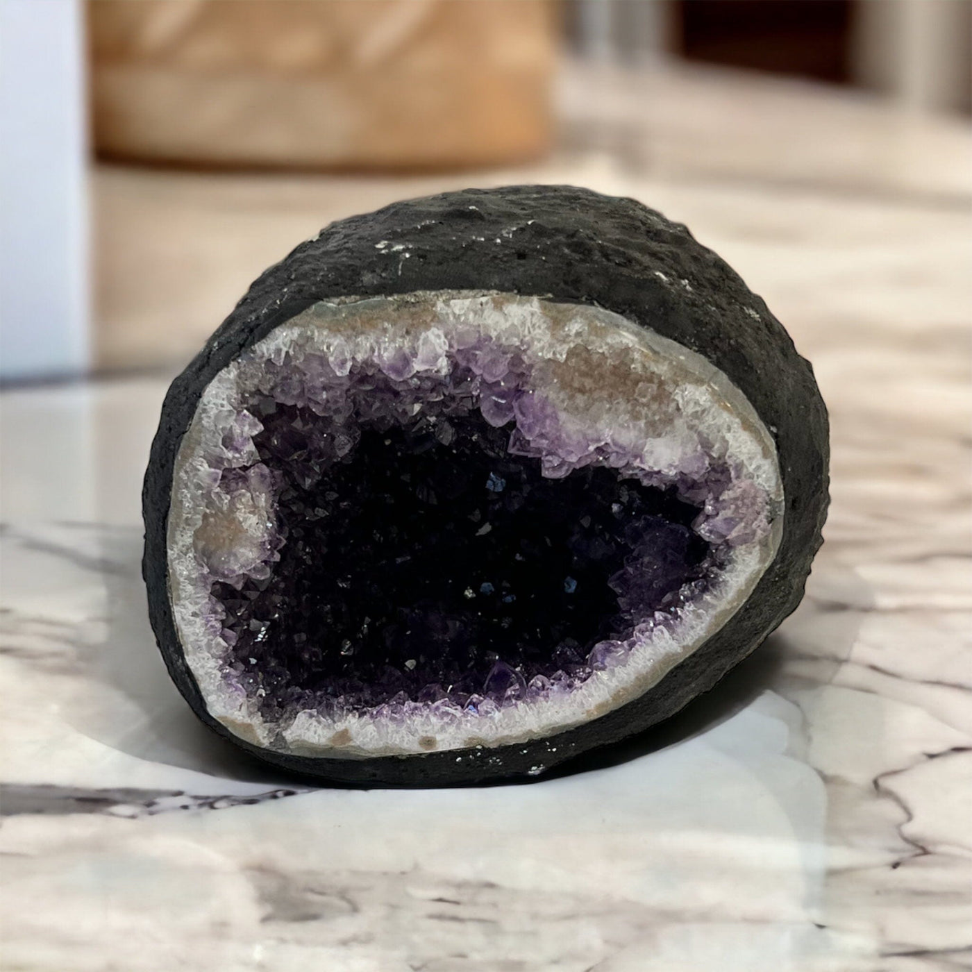 Round amethyst geode on white marble counter top.
