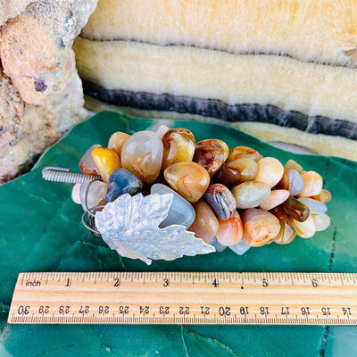 Aerial view of Agate Stone Grape Bunch with Silver Leaf, laying next to a ruler for size reference.