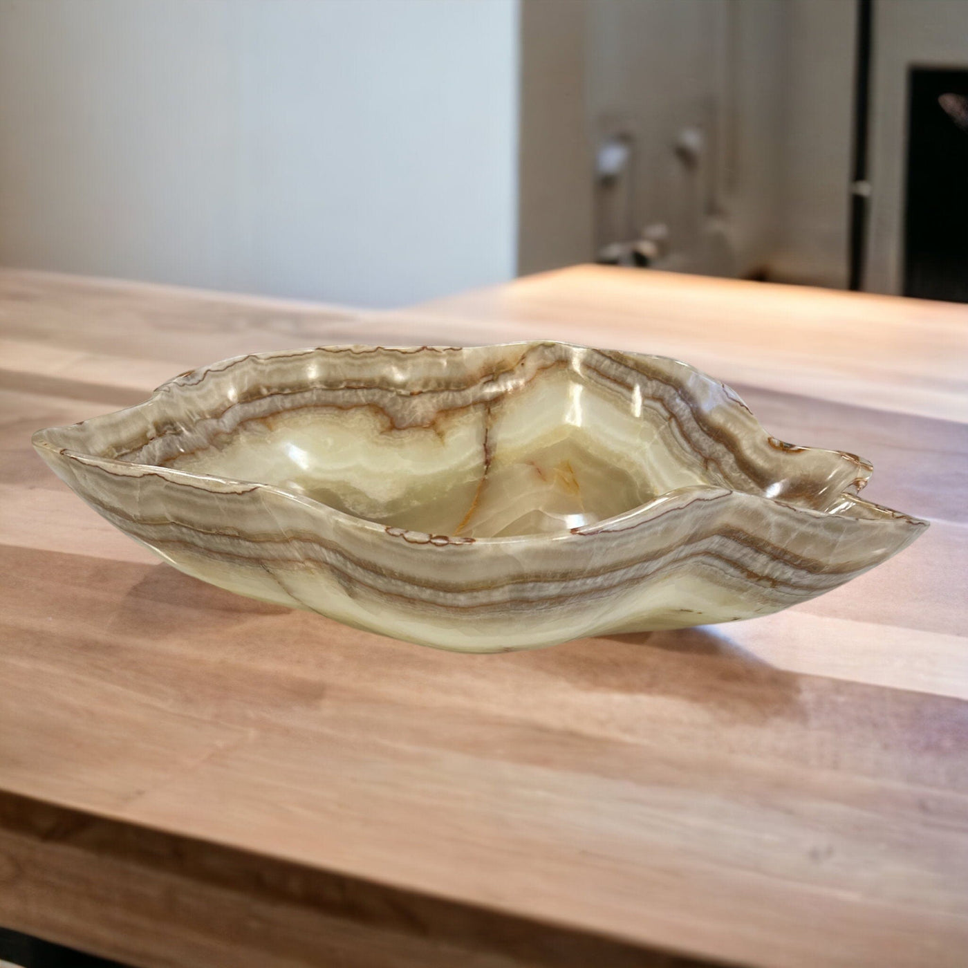 Mexican onyx bowl in shades of cream, tan, brown and white displayed on a counter top.