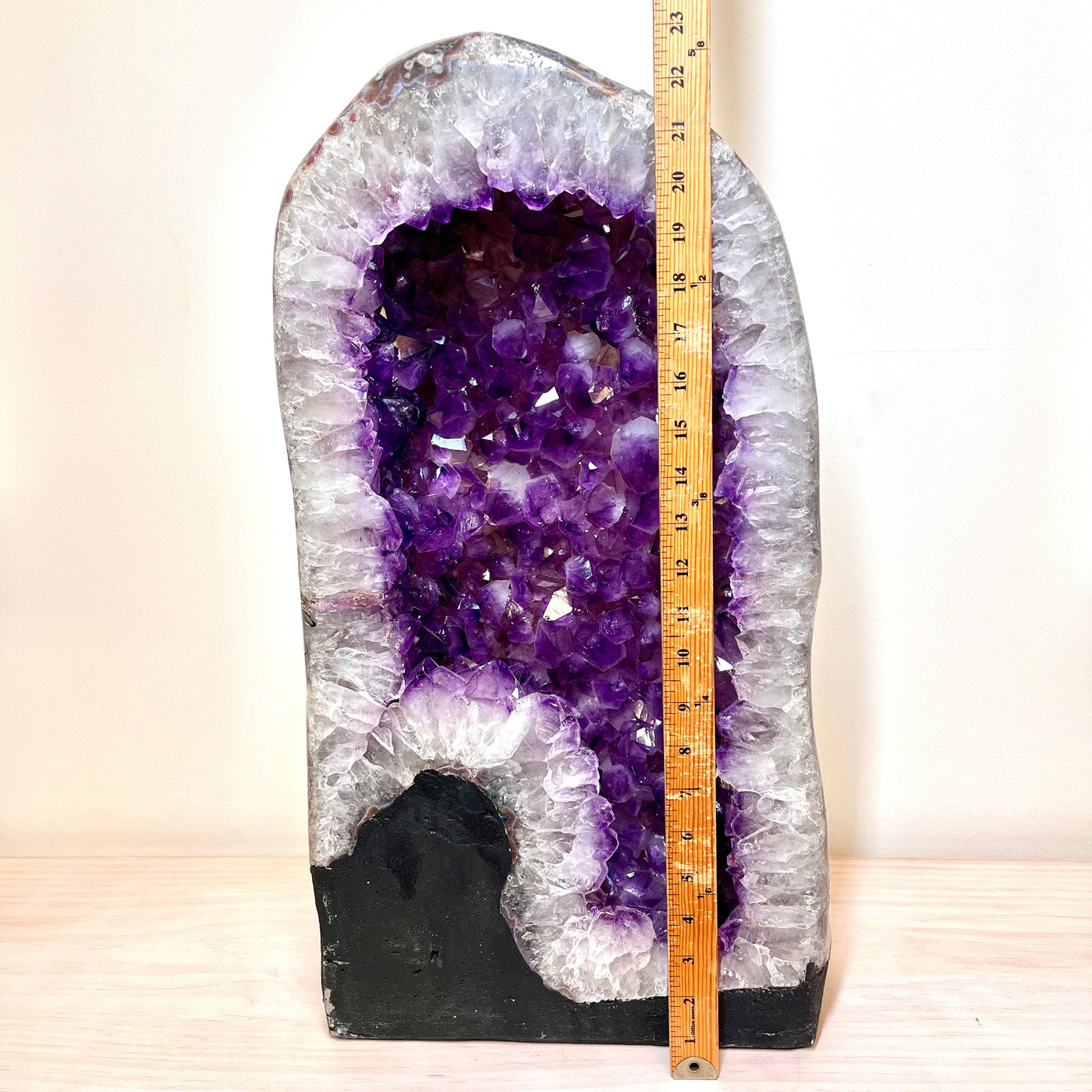 Frontal view of the Polished Amethyst Geode Cathedral, next to an upright yard stick for height reference.
