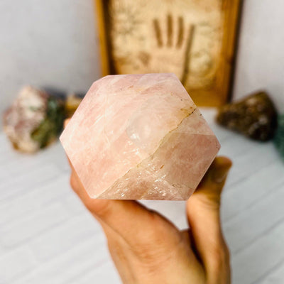 Aerial view of the tip of Rose Quartz Polished Tower, held up by woman's hand.