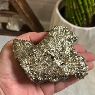 Backside of Pyrite with Hematite cluster in a woman's hand.