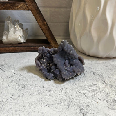 Grape Agate Botryoidal Purple Chalcedony Formation with decorations in the background