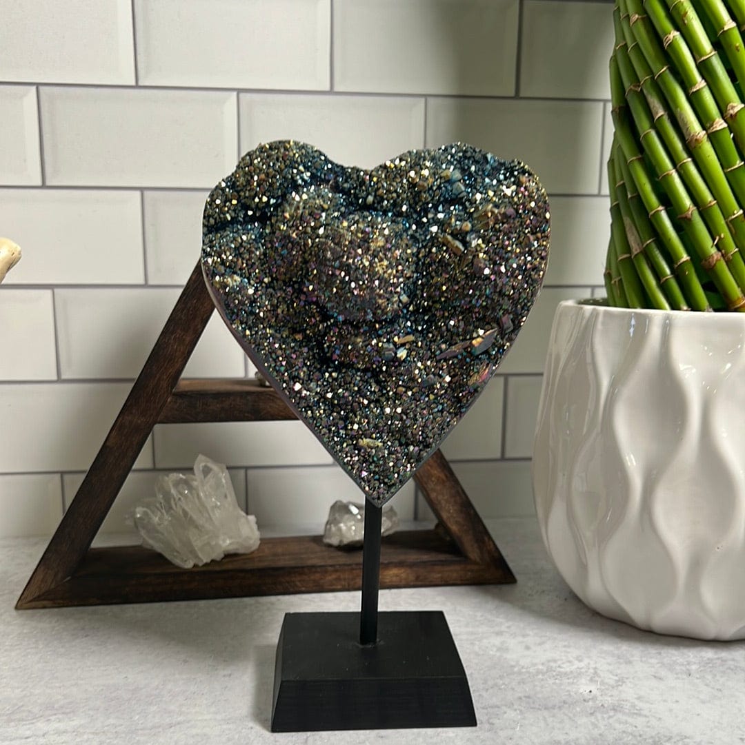 Amethyst heart coated with rainbow titanium on a black wood stand.