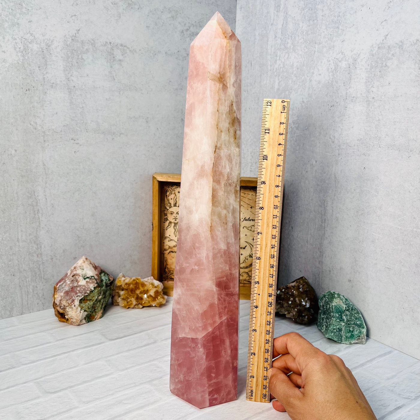 Side view of the Rose Quartz Polished Tower, placed next to an upright ruler for size reference.