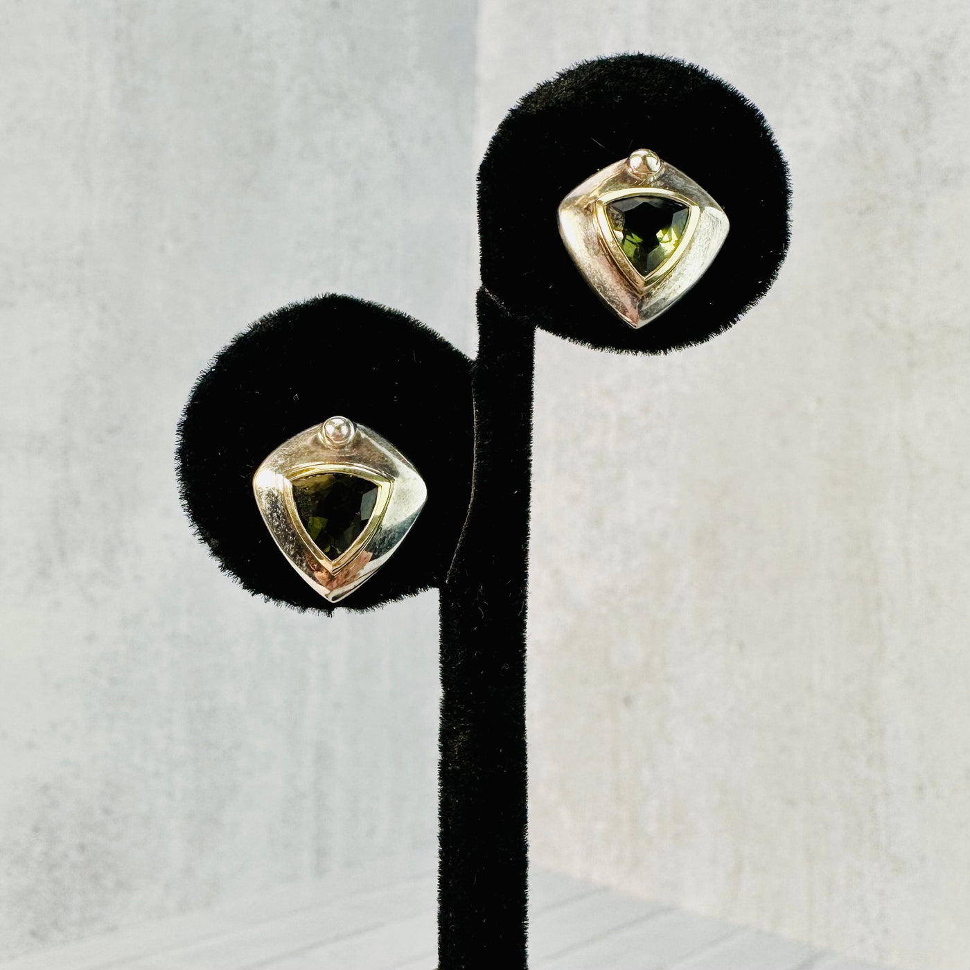Moldavite earrings displayed on a black earring display.