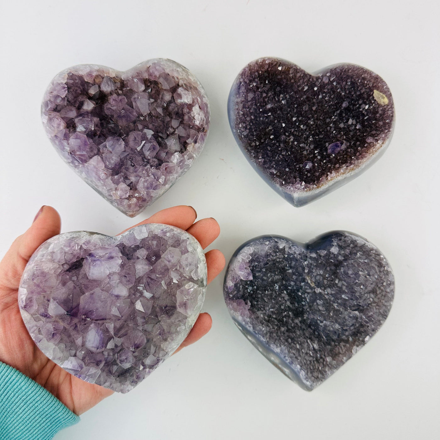 Amethyst Crystal Hearts with one in a hand for size reference